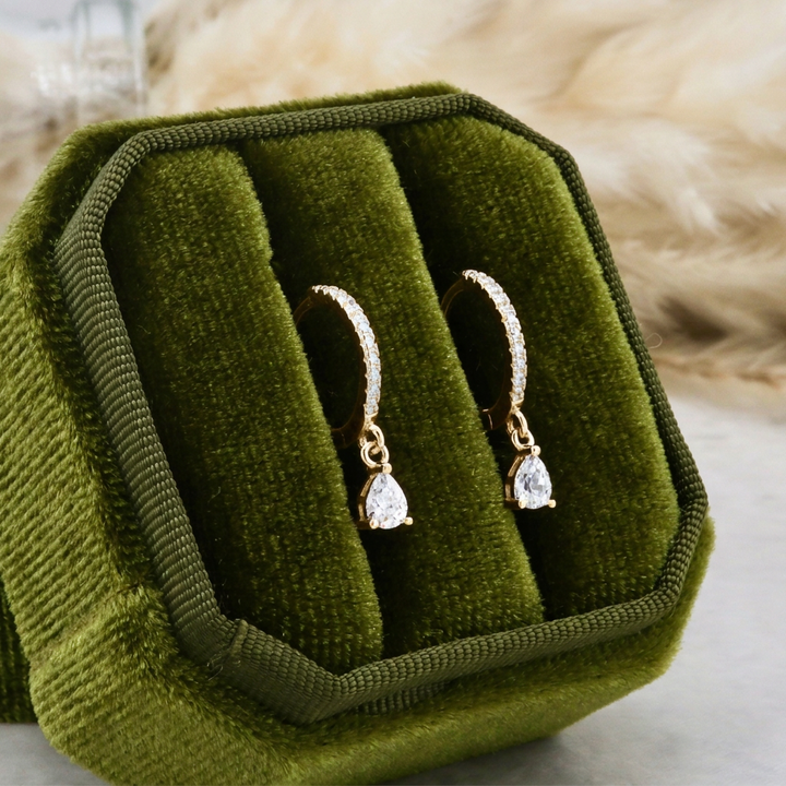 Boucles d’oreilles Huggies gouttes dorées, présentées dans un écrin velours vert